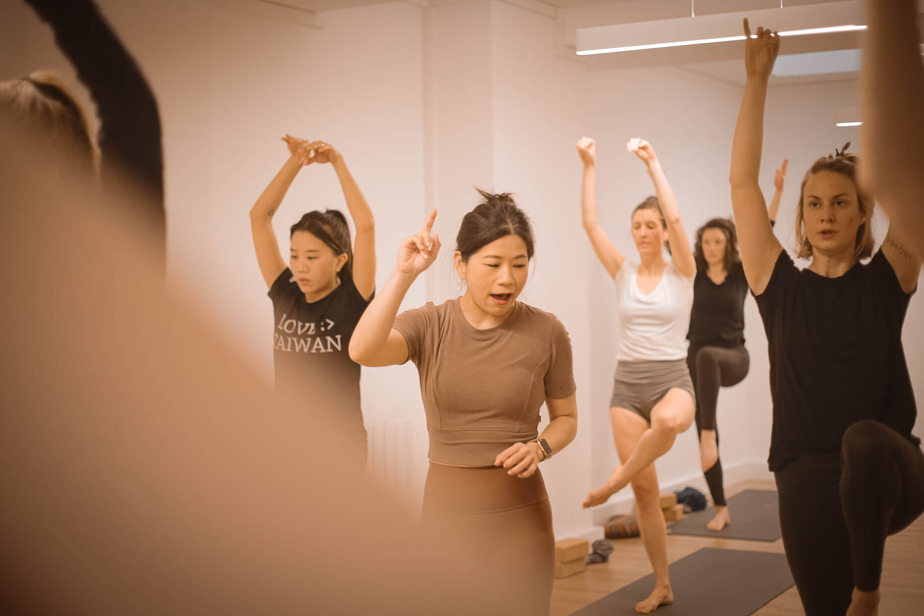 Lara, professeur de Yin Yang Yoga, au milieu des élèves debout dans une posture d'équilibre (posture de la cigogne - Stork Bird Pose) pendant la formation 30h de Yang à l'Académie Yoga Paris.