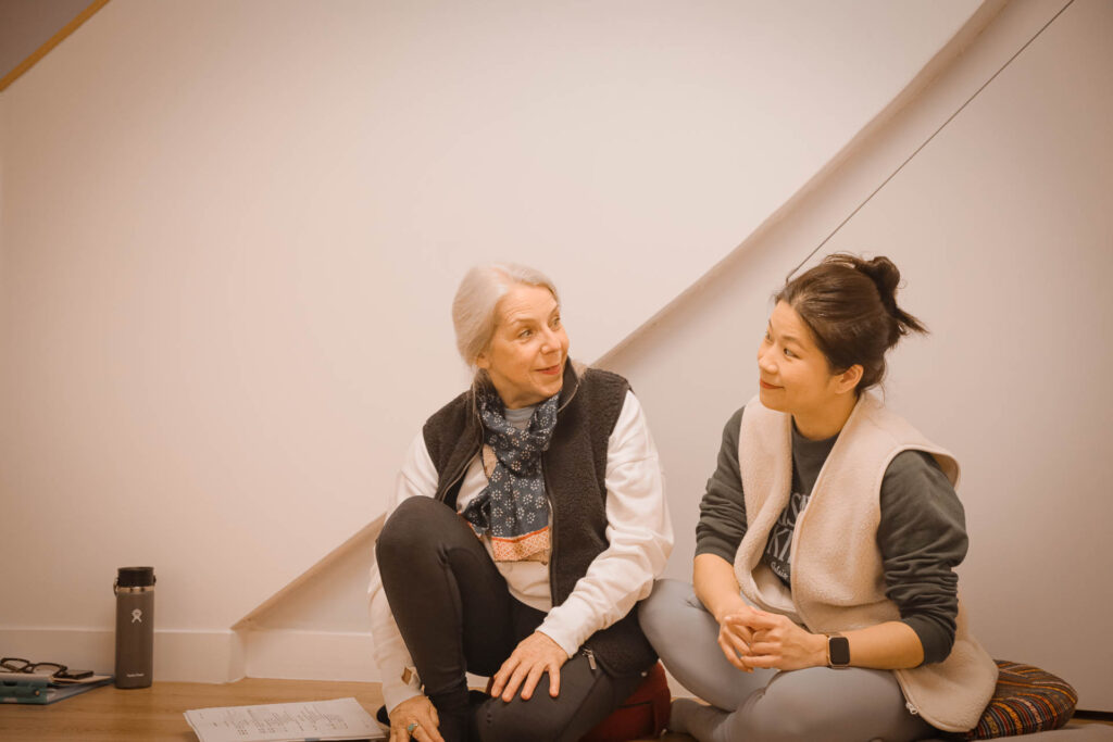 Lara et Isabel, deux professeurs expérimentées de la formation Yin Yoga 200h, se regardent et sourient à l'Académie Yoga Paris 15.