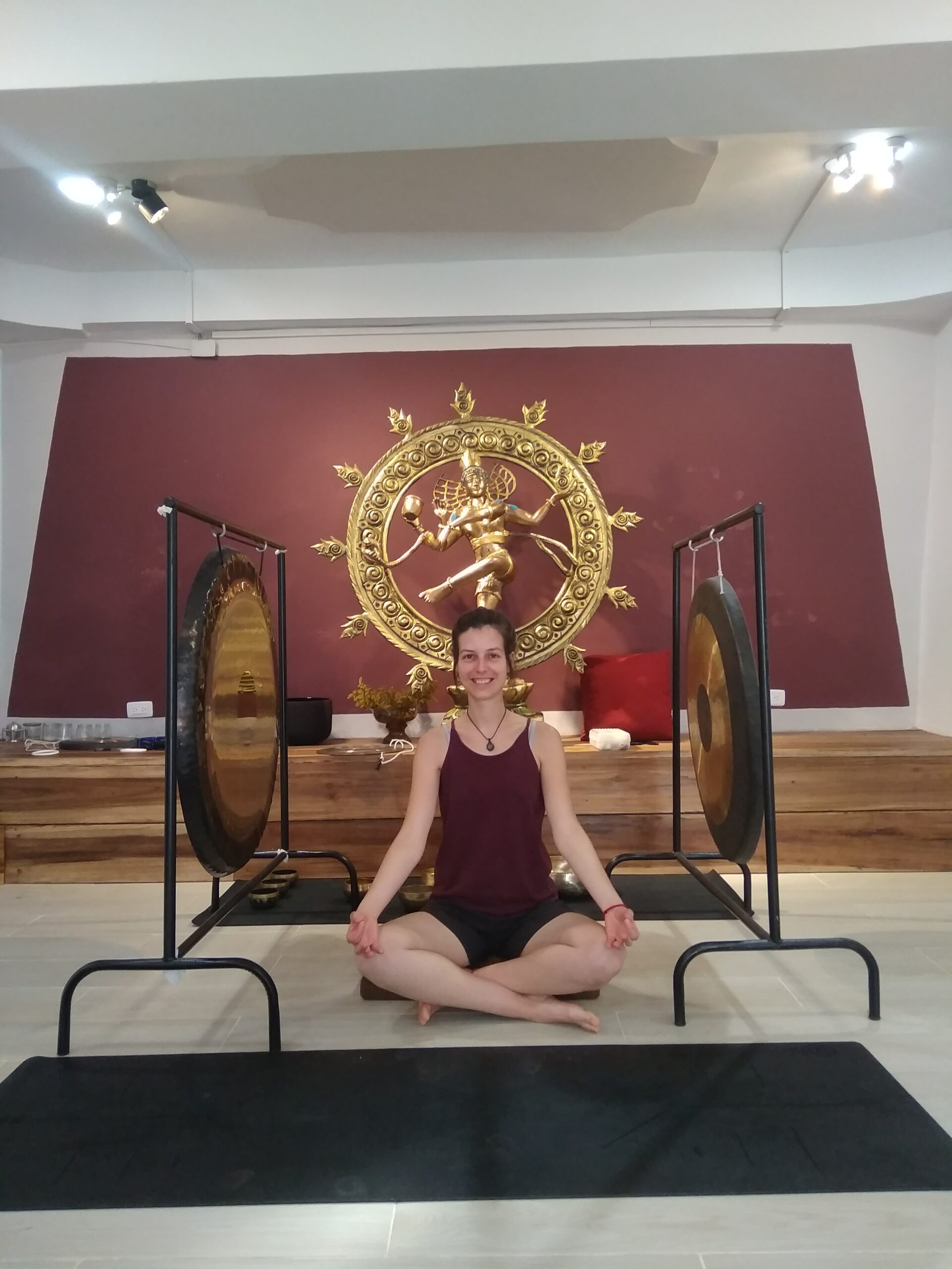 Une femme assise sur le tapis de yoga entourré par les gongs. Elle fait partie de l'équipe pédagogique pour la formation du Yin Yoga.