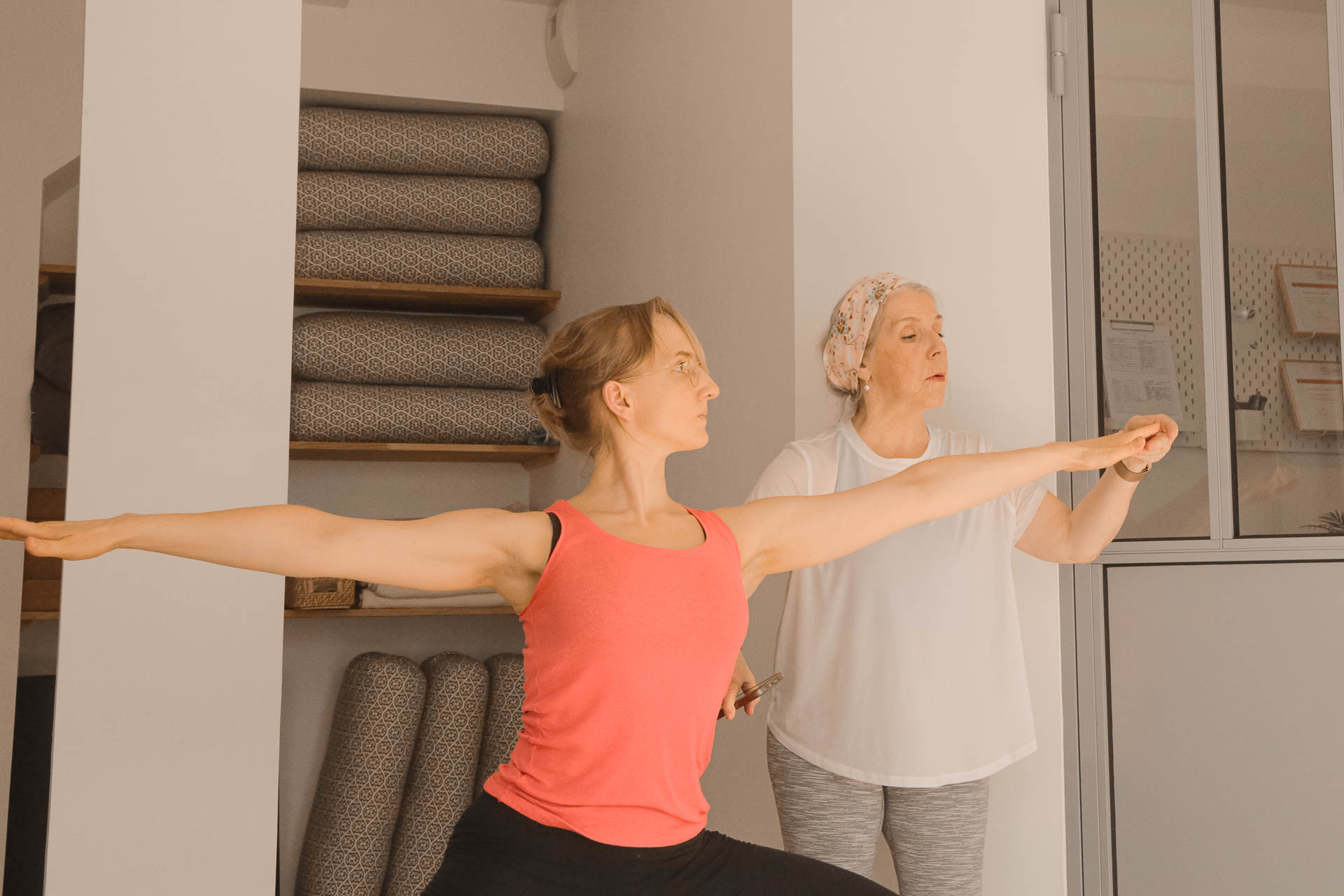 Isabel ajuste le bras d’une élève en posture de Guerrier 2 pendant la formation 200h Hatha Yoga au studio du XVe arrondissement de Paris.