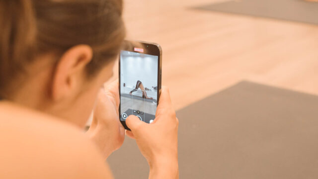 Élève prenant en photo une posture sur la tête pendant l’Asana Lab de la formation 200h Hatha Yoga au studio du XVe arrondissement de Paris.