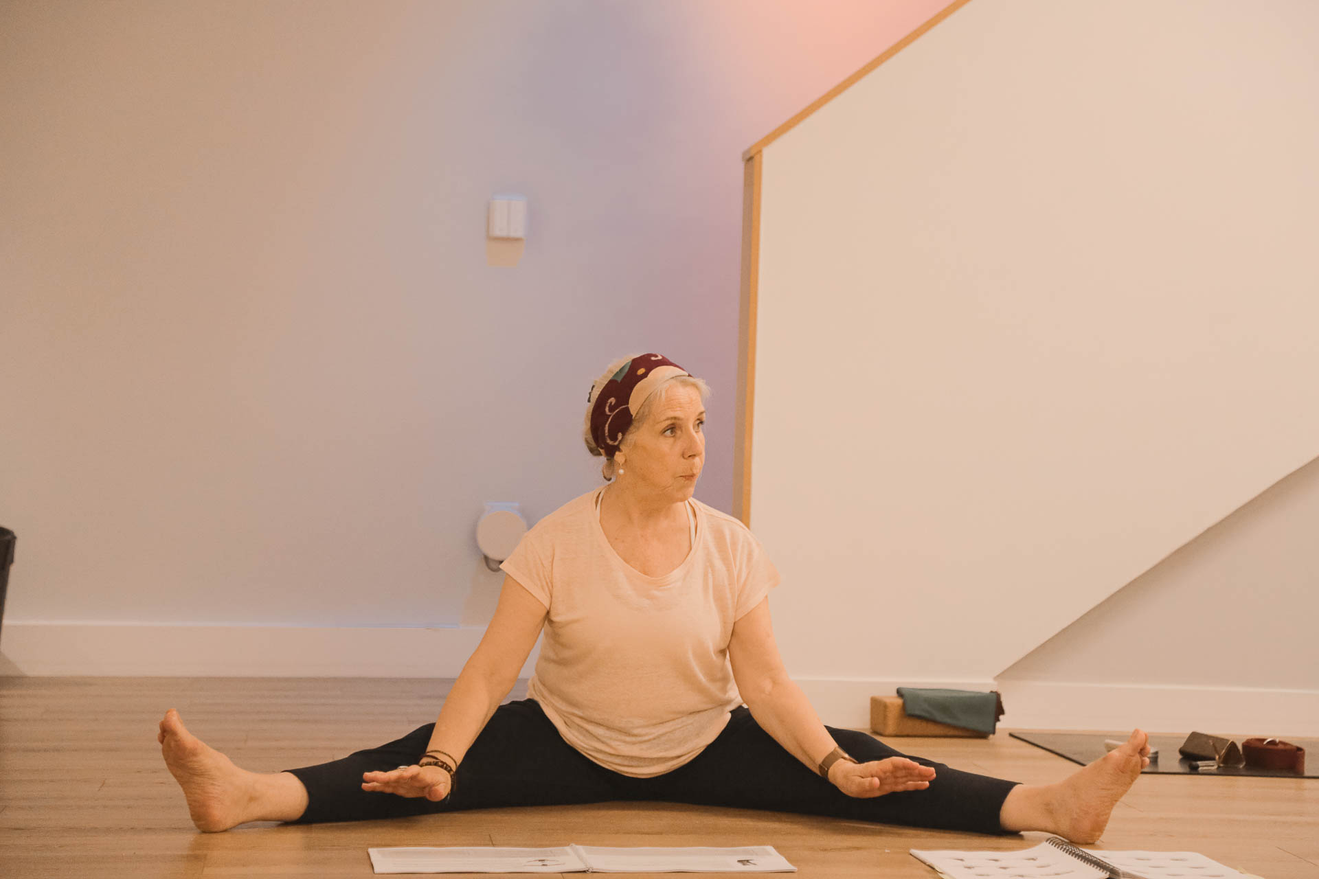 Isabel en grand écart expliquant une posture de Hatha Yoga durant la formation 200h au studio du XVe arrondissement de Paris.